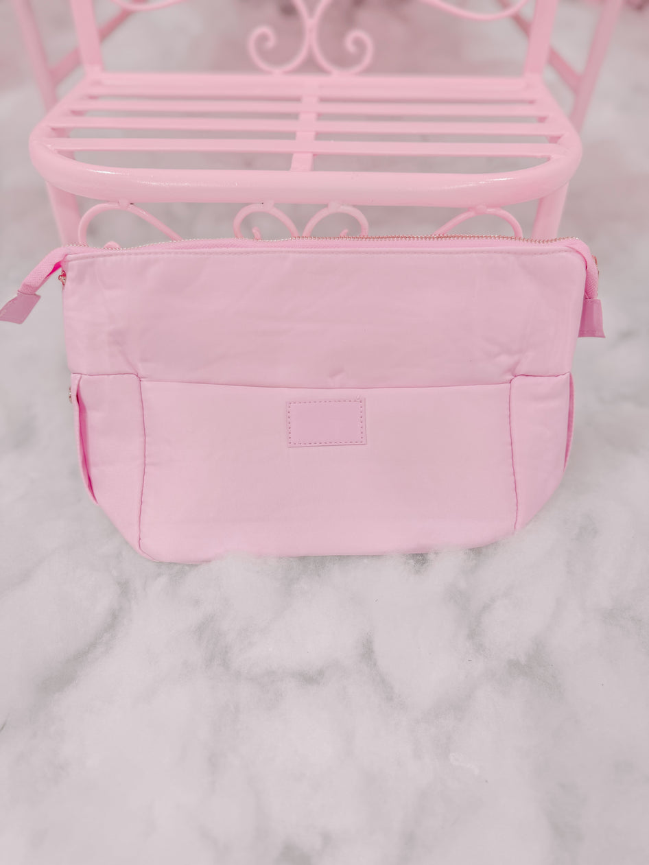 Light pink zippered pouch on a marble surface.
