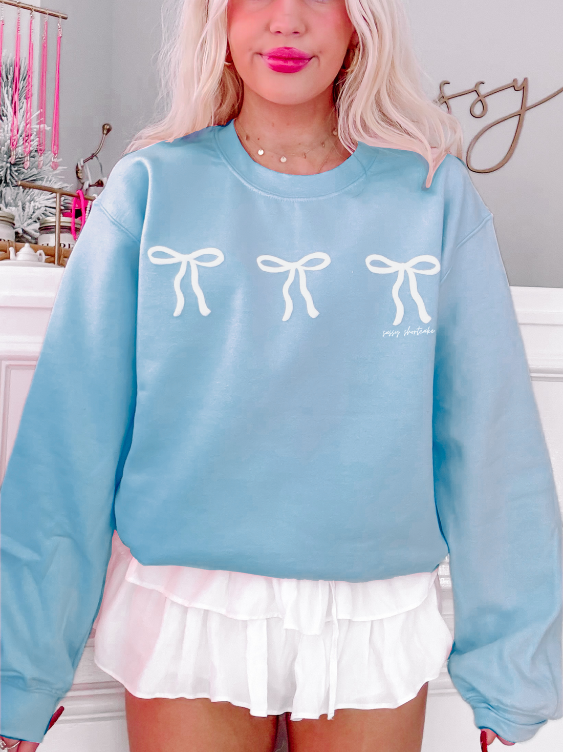 Light blue Blushing Bow Crewneck sweatshirt with three white bows.
