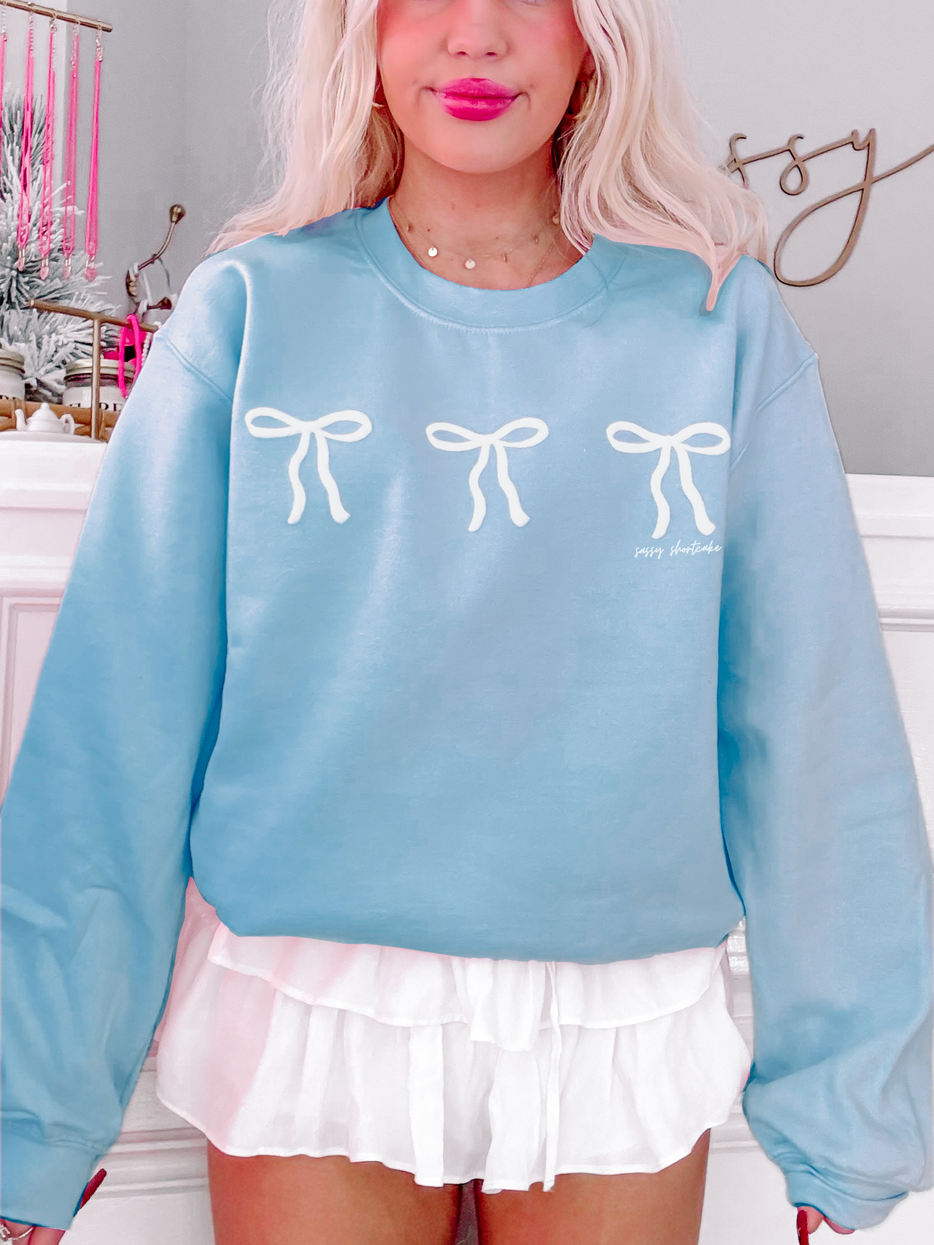 Sassy Shortcake Blushing Bow Crewneck Sweatshirt, light blue, features three white bows.
