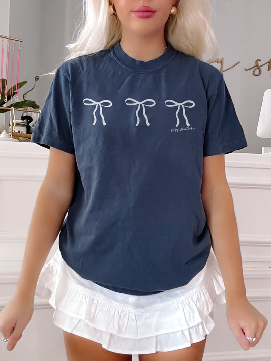 Sassy Shortcake Blushing Bow Tee in navy blue, featuring three white bows.
