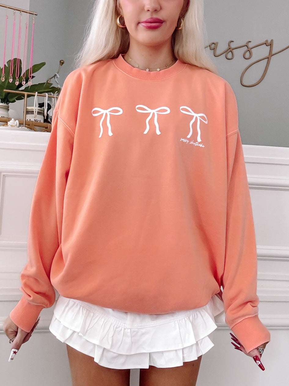 Orange Blushing Bow Crewneck sweatshirt with three white bows; Sassy Shortcake design.
