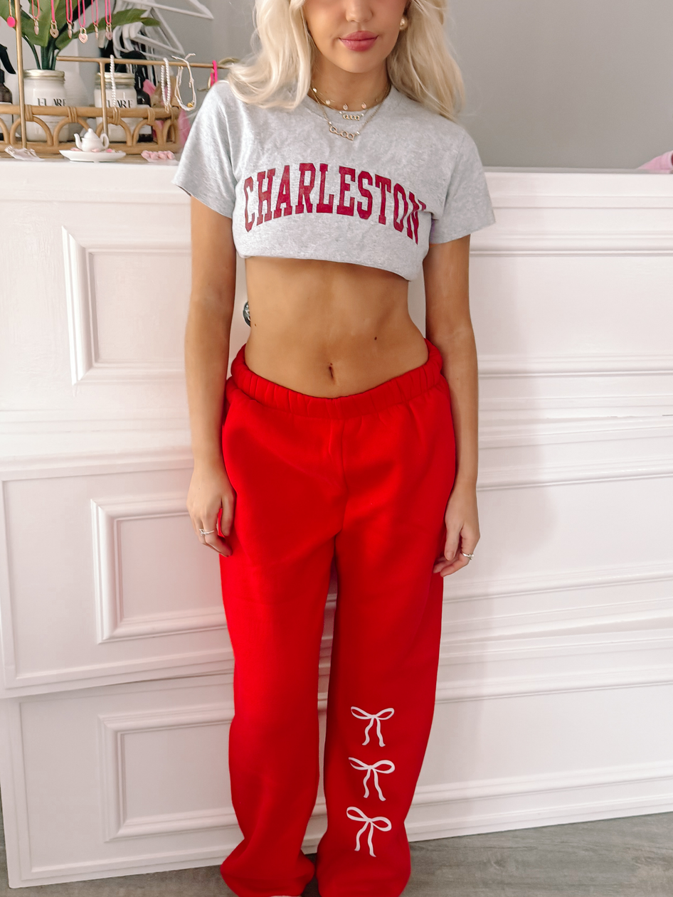 Red sweatpants with delicate white bows, styled against a white backdrop.
