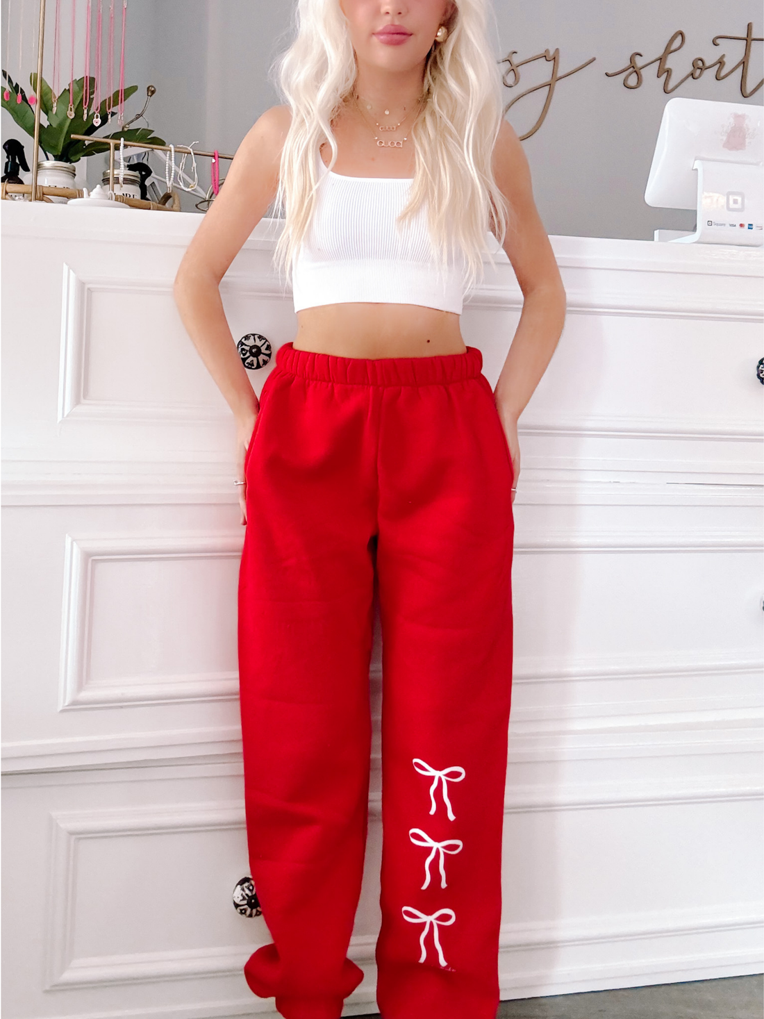 Red sweatpants with a playful white bow design, shown on a model against a white backdrop.
