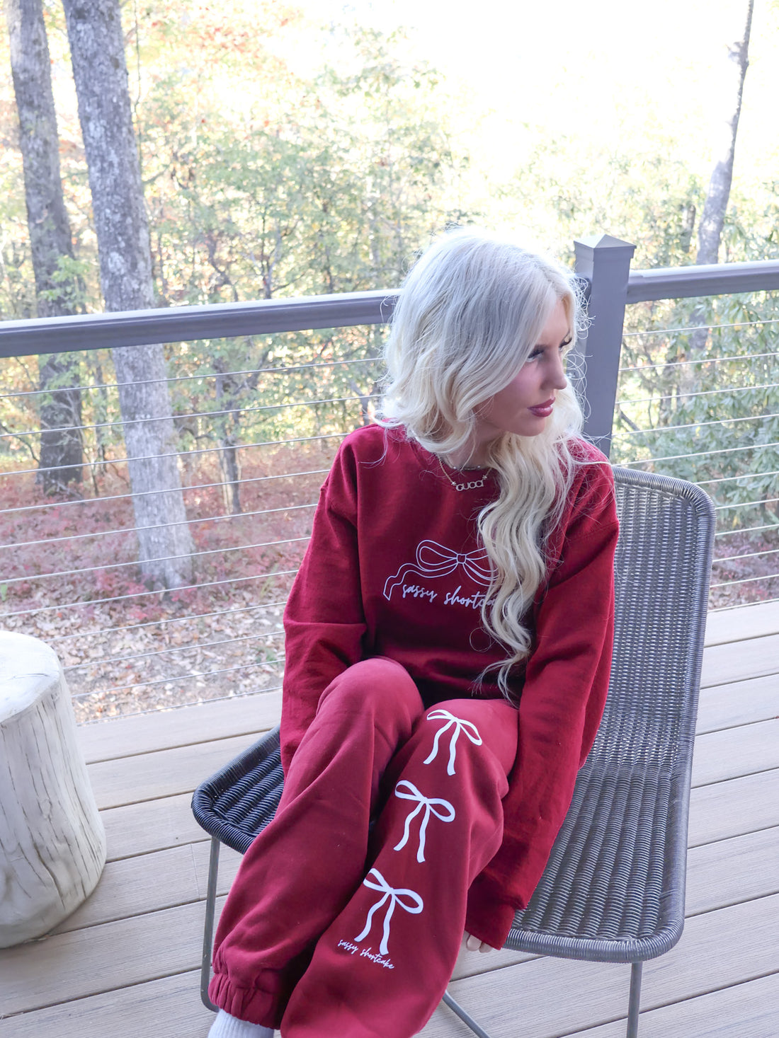 Close-up of the burgundy sweatpants, highlighting the white 'Sassy Shortcake' text, three white bows, and micro-fleece lining detail.