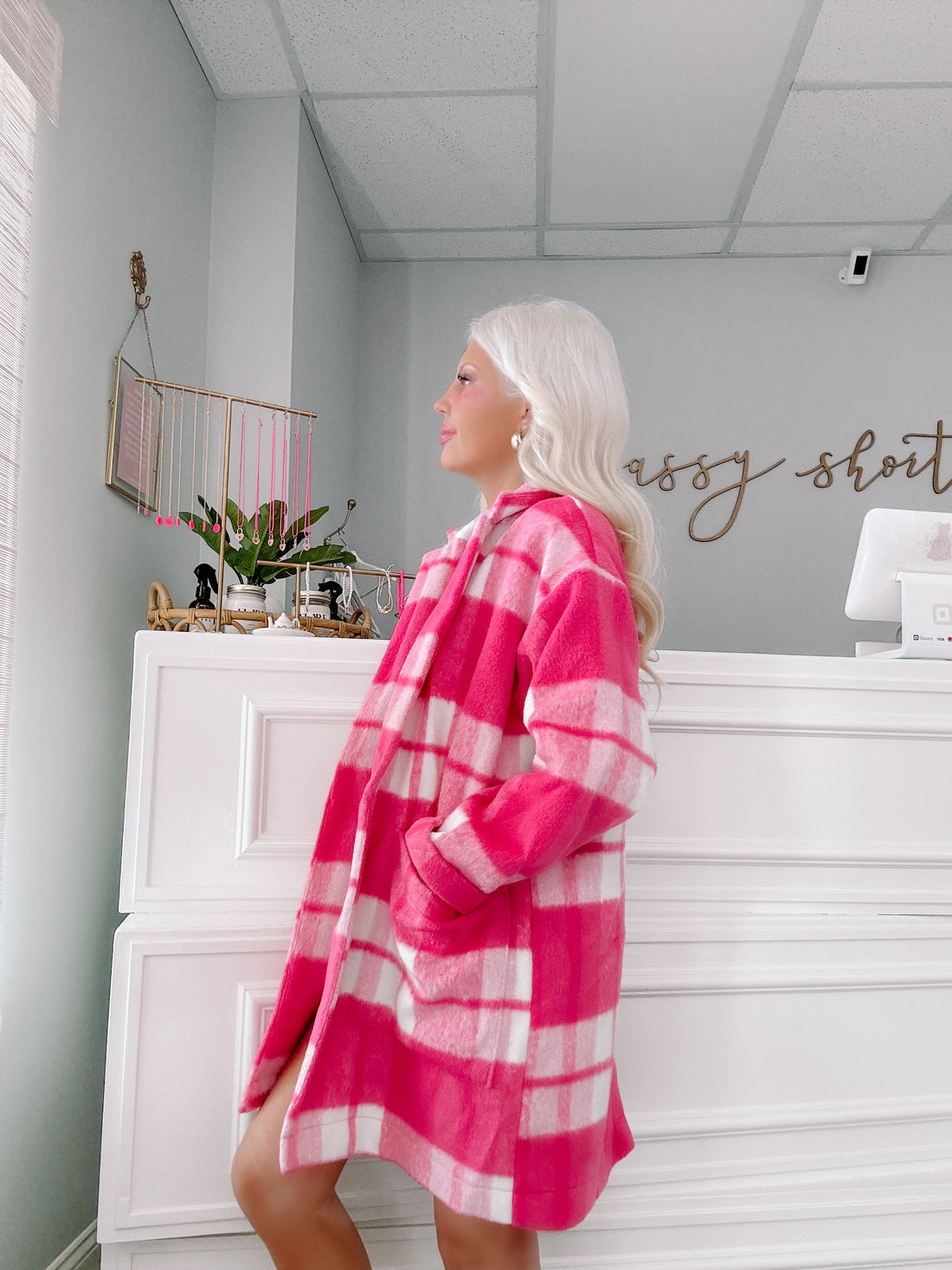 Pink and white checked jacket; cozy, oversized fit shown in a boutique.
