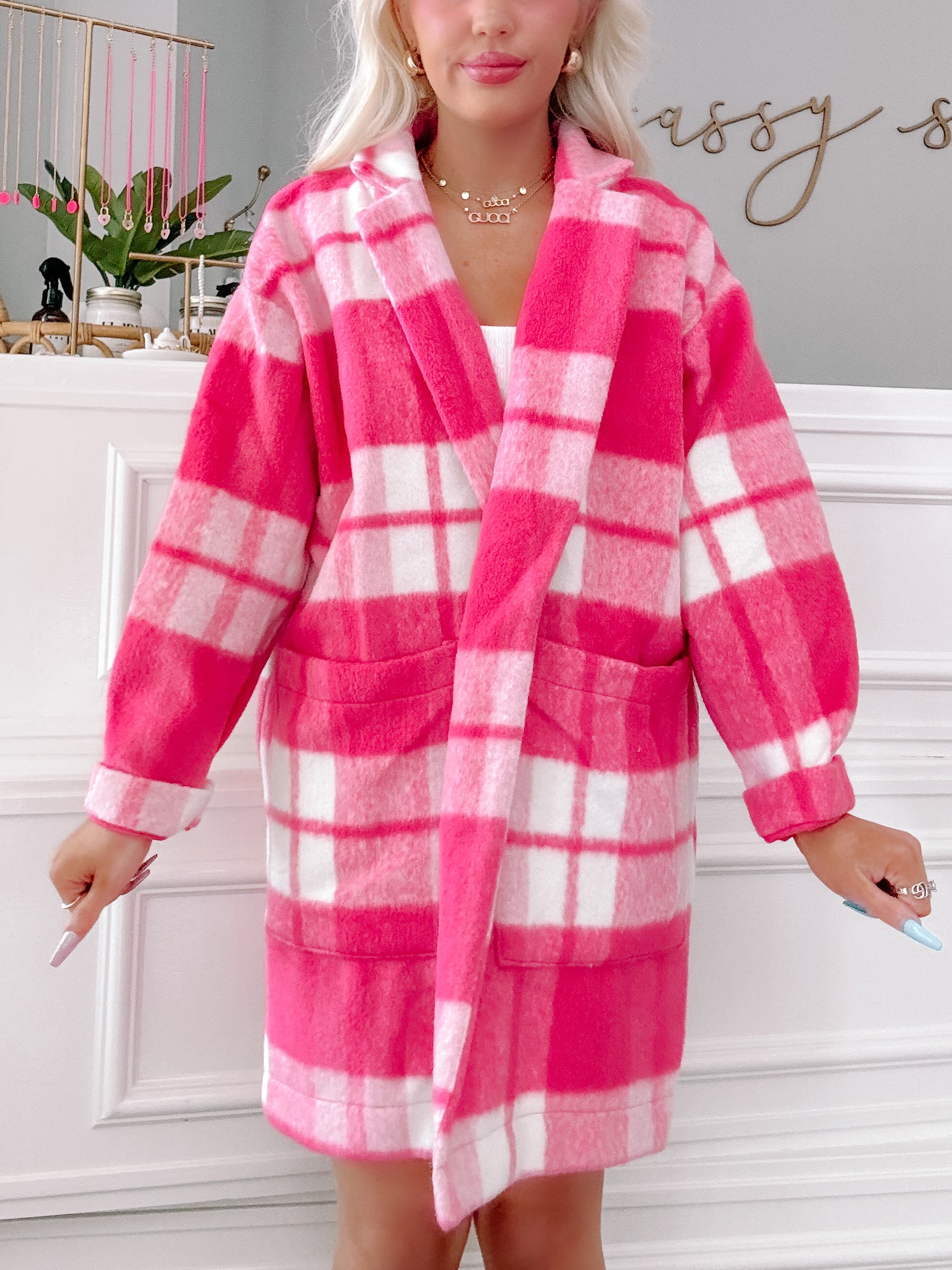 Pink and white checkered fleece jacket with pockets, shown on a model.
