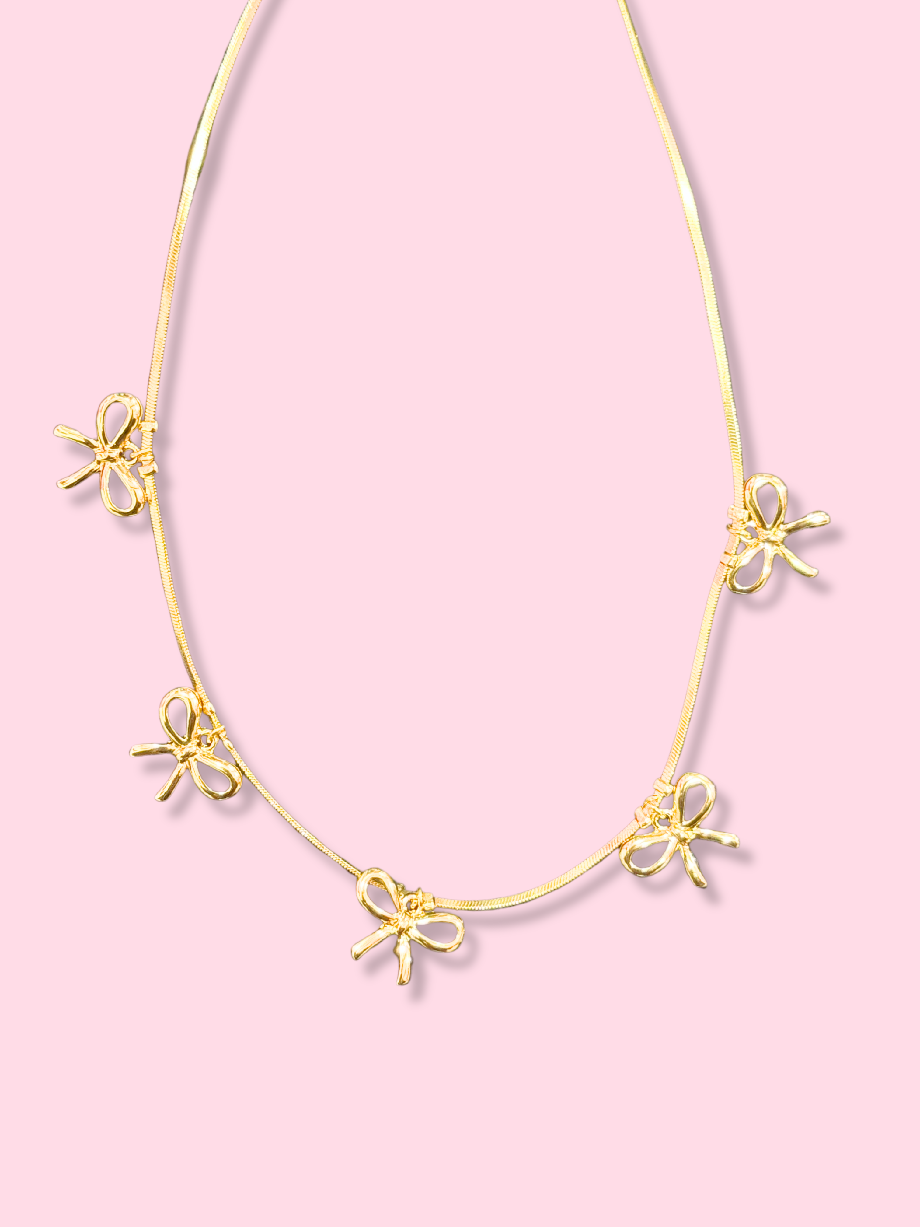 Gold Bow & Repeat necklace with four charming bow charms.
