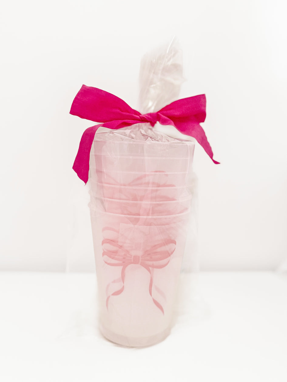 Pink Bow Cups: Set of frosted pink cups with pink ribbon accents, perfect for parties.
