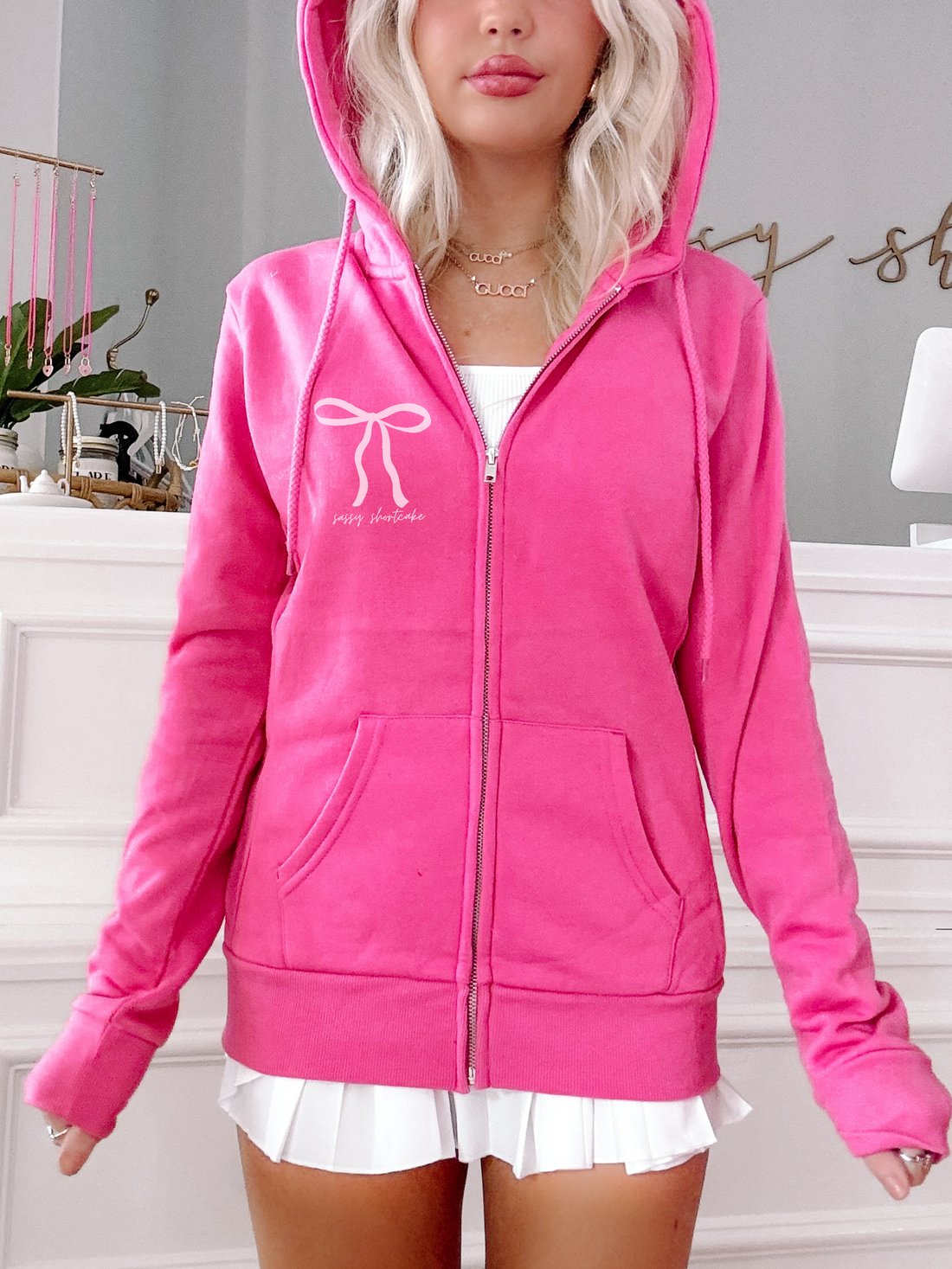 Hot pink zip-up hoodie featuring a bow design; shown on model.
