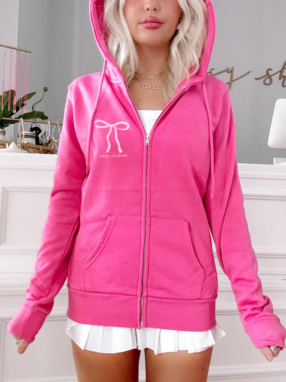 Hot pink zip-up hoodie with bow detail, showcased on a model.
