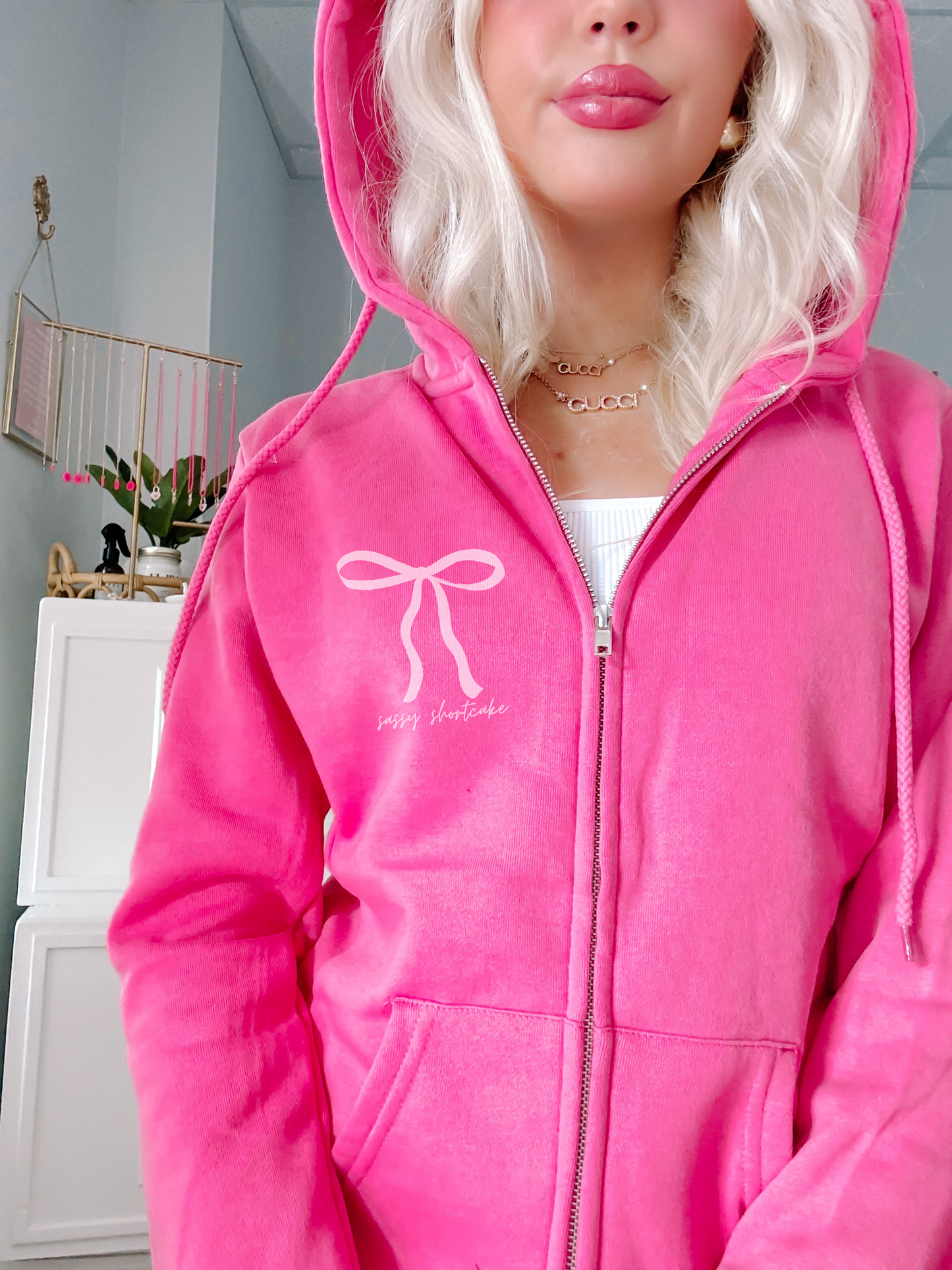 Hot pink zip-up hoodie featuring a bow design, showcased on a model.
