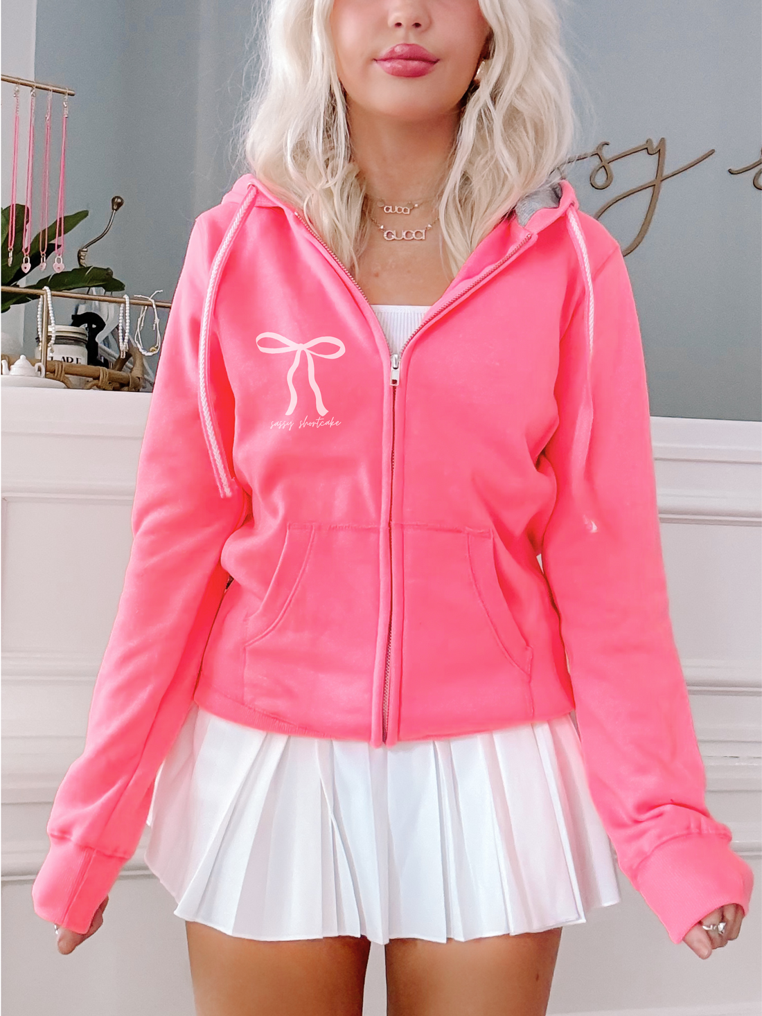Neon pink zip-up hoodie, bow detail, "Sassy Shortcake" logo.
