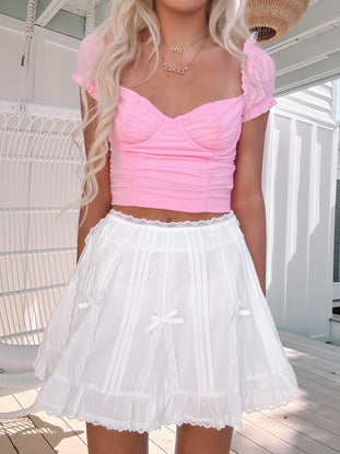 Model in the Bows & Lace white mini skirt with lace trim and bow ribbon accents.