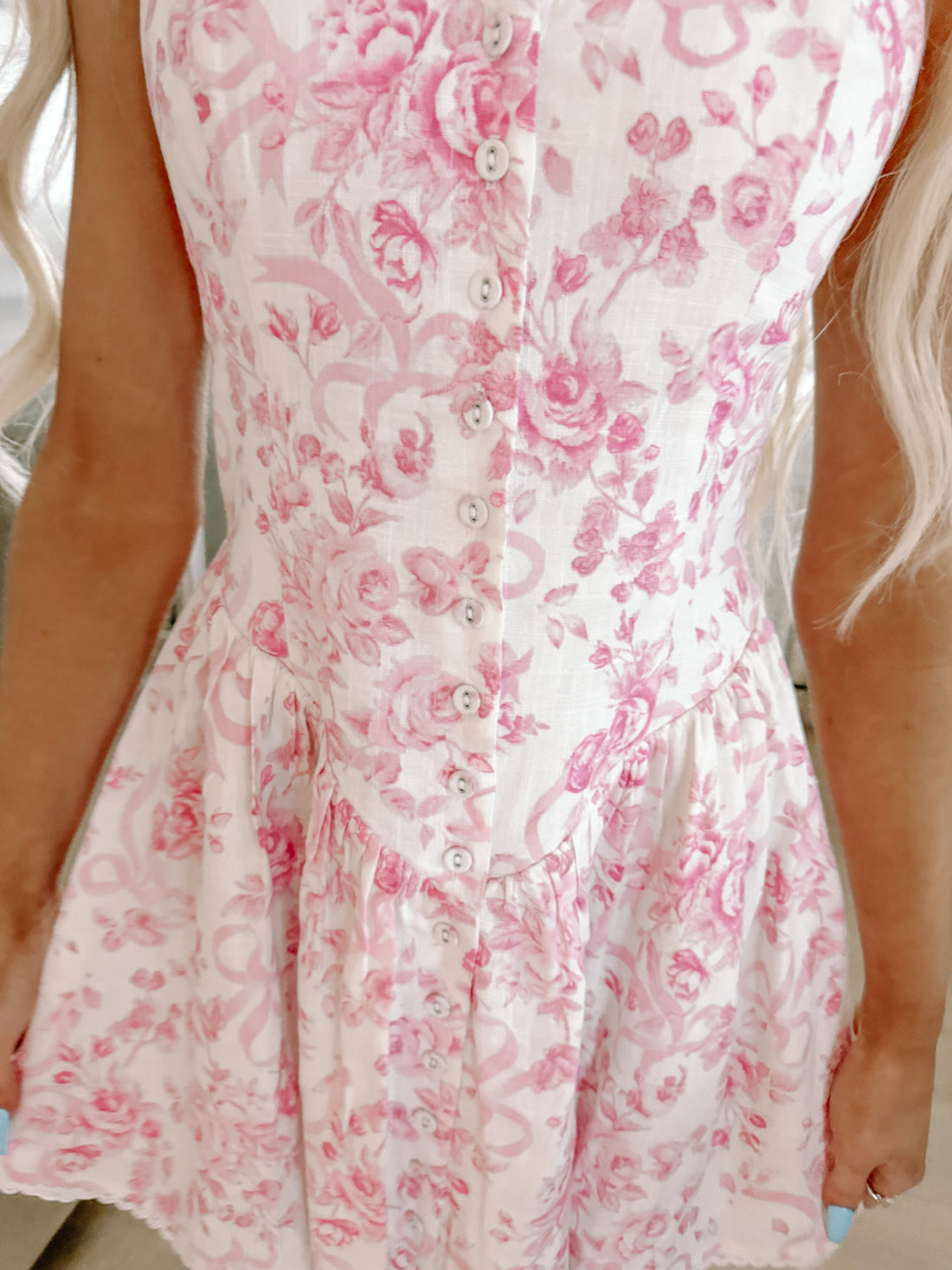Pink floral dress with button front, close-up view showing fabric detail.
