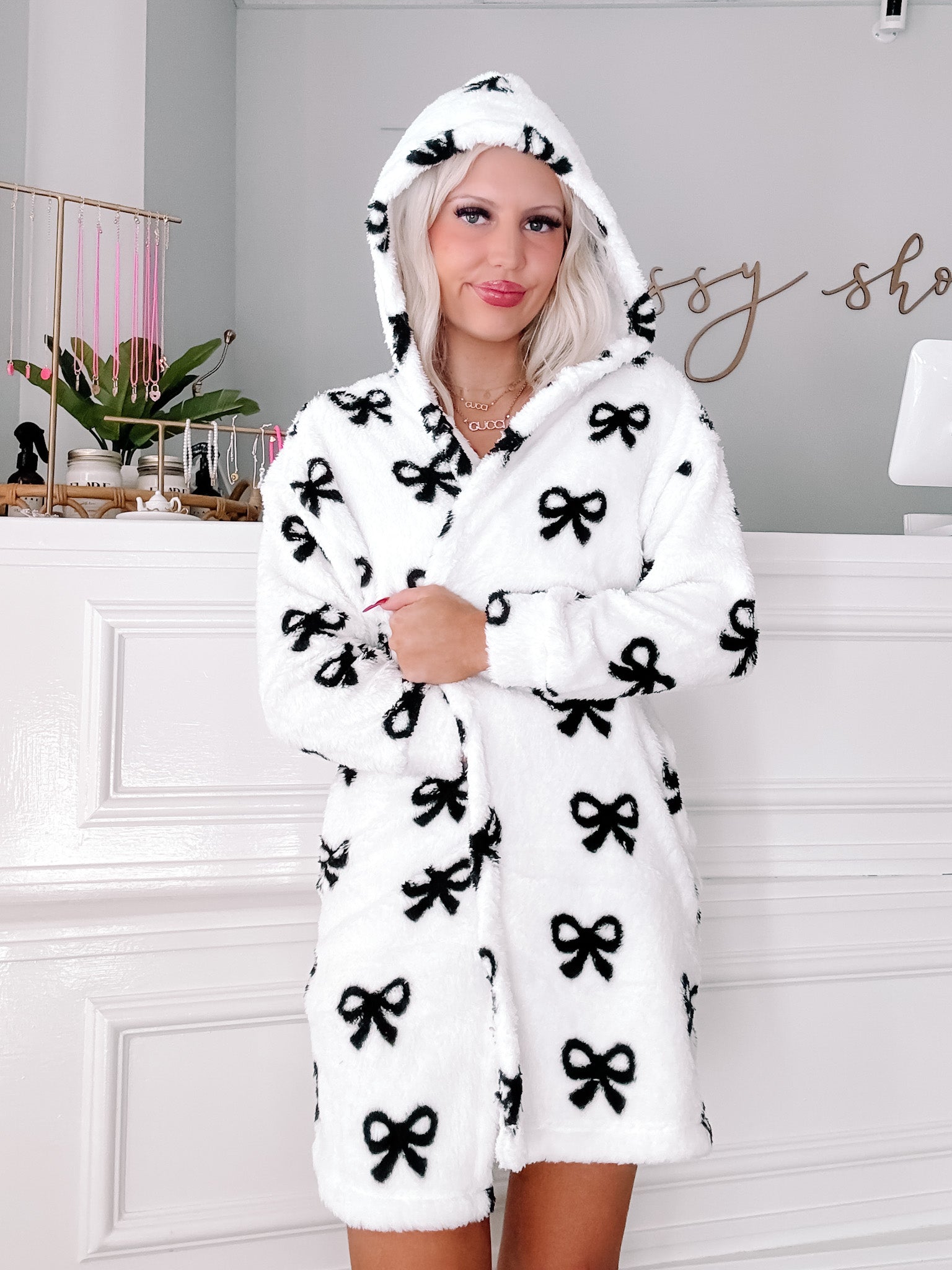 White hooded robe with black bow print, cozy plush fabric.
