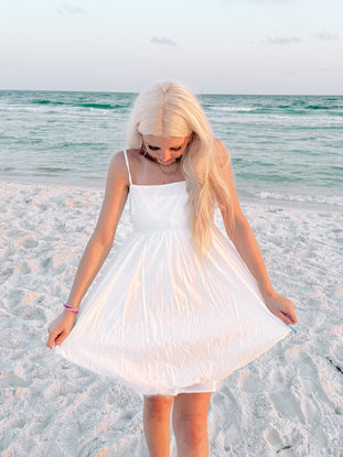White sundress on a beach, ocean backdrop
