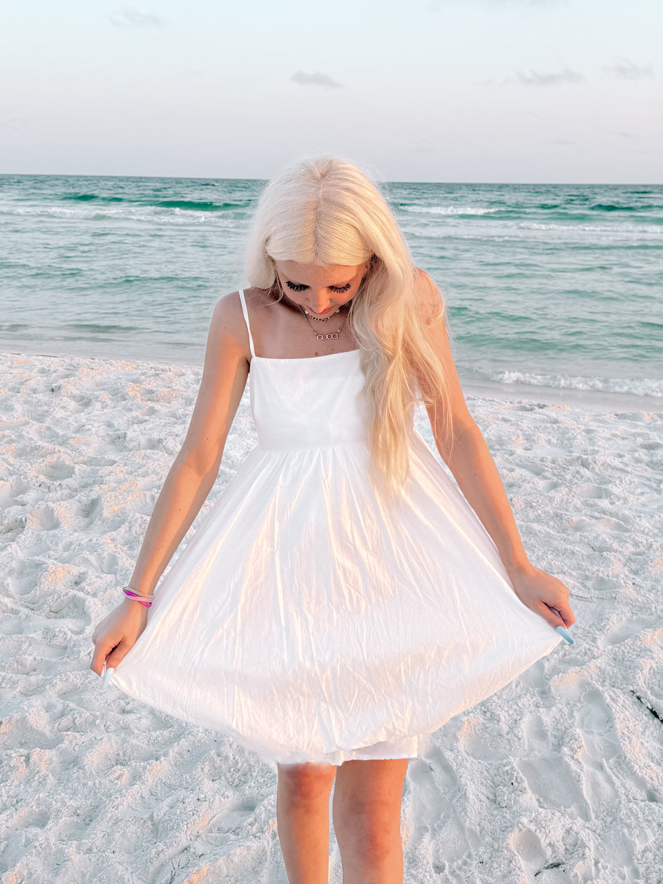 White sundress on a beach, ocean backdrop
