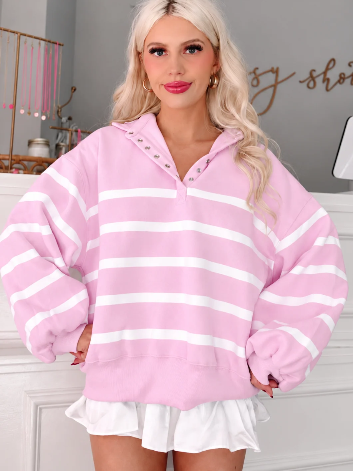 Model wearing the Brynn Baby Pink Stripe Pullover with white shorts for a preppy, casual look from Sassy Shortcake
