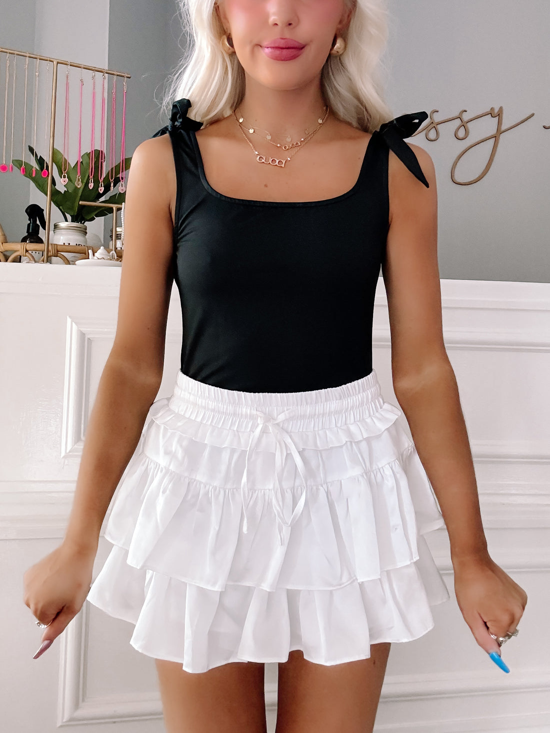 Black Brynn bodysuit with tie straps, paired with a white ruffled mini skirt.

