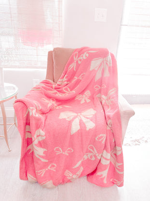 Bubblegum Pink Bow Blanket: Soft, plush pink blanket with off-white bow pattern.
