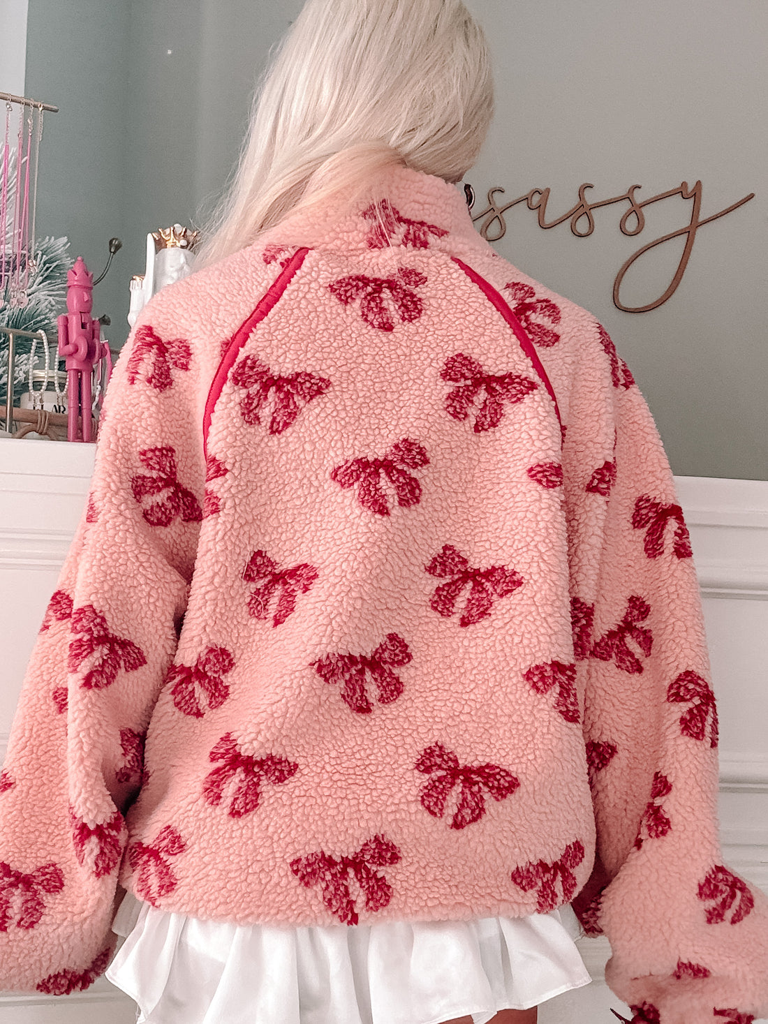 Pink sherpa pullover with a red bow print, shown from the back.
