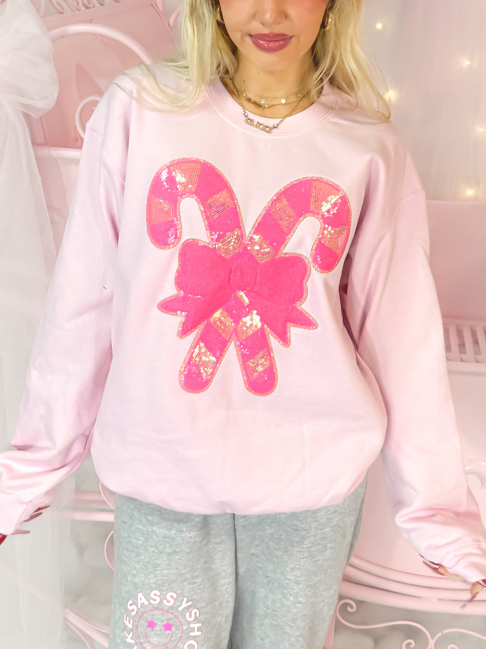 Pink crewneck sweatshirt featuring a sparkly candy cane design.
