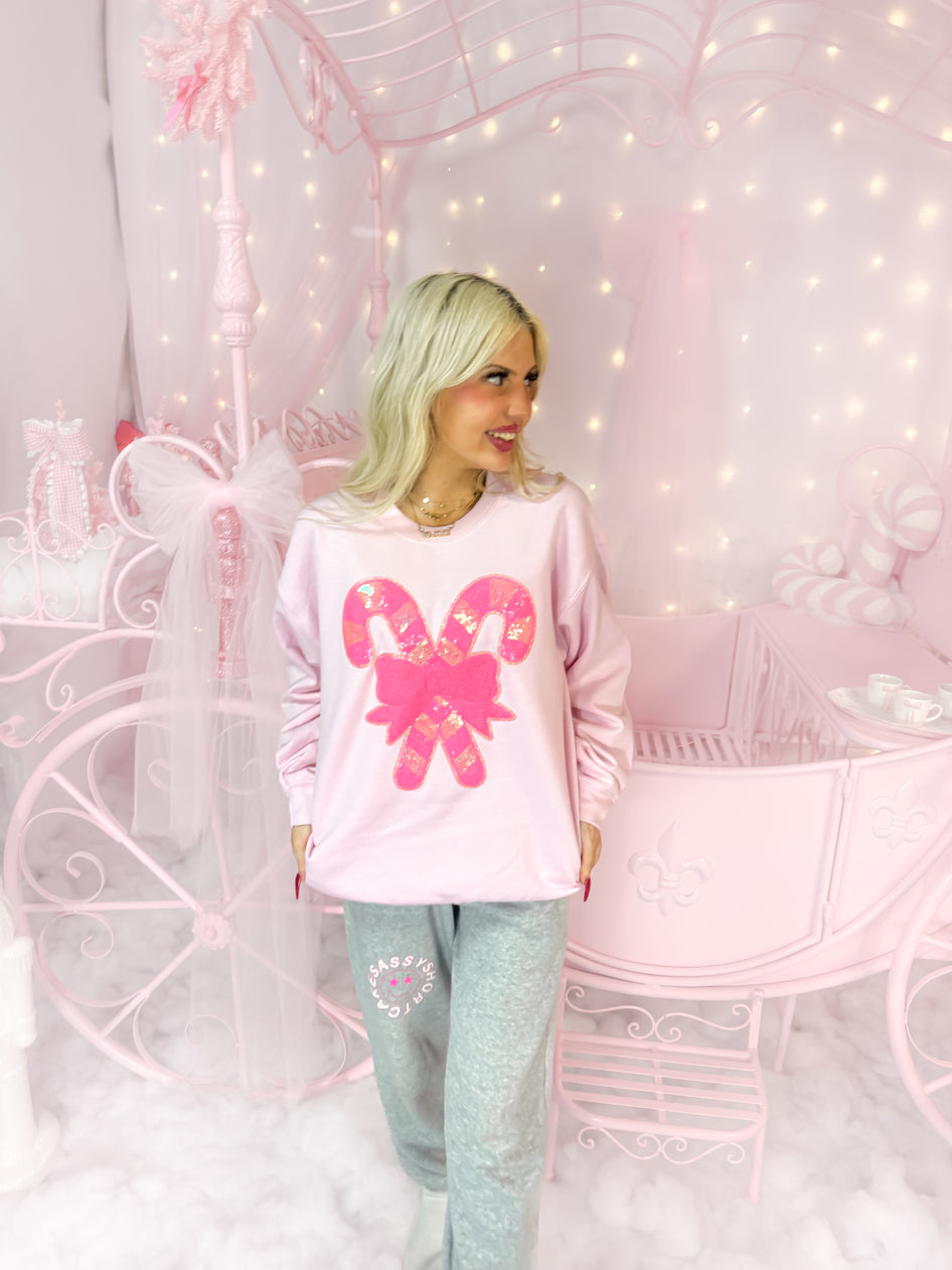 Pink candy cane sweatshirt styled in a pastel pink room.
