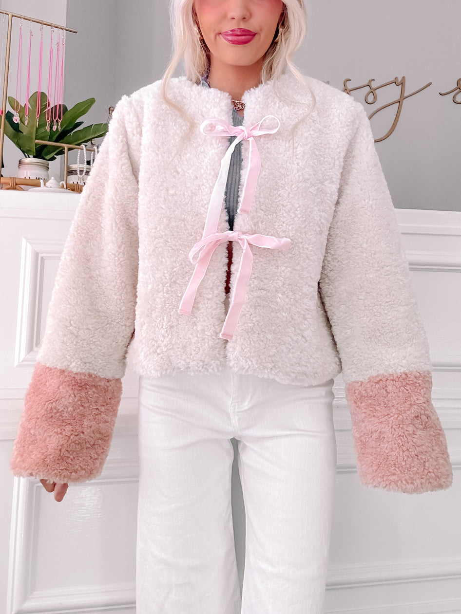 Cream sherpa Charmed jacket with blush pink cuffs and satin ribbon tie.
