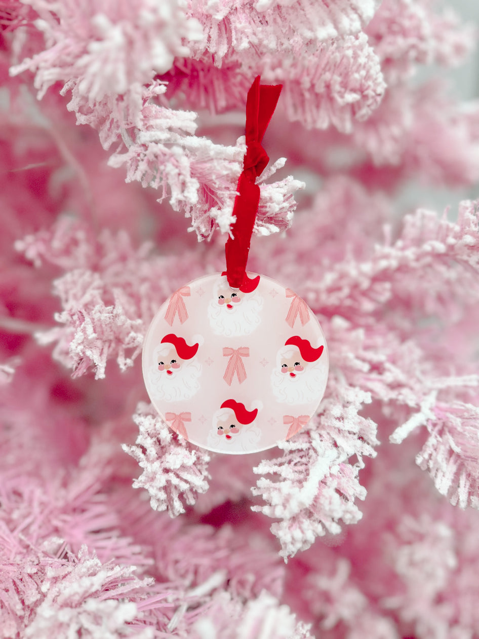 Pink frosted Christmas tree with a round Santa ornament, red ribbon.

