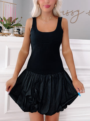 Black mini dress with a fitted bodice and a puffy, voluminous skirt; shown on a model.
