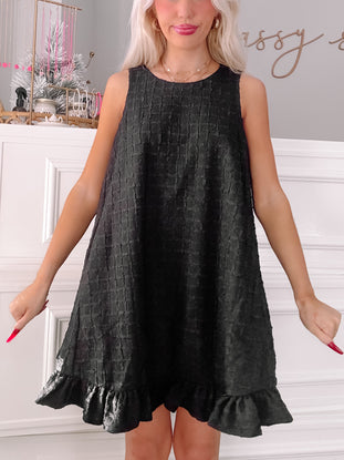 Black textured mini dress with ruffle hem.
