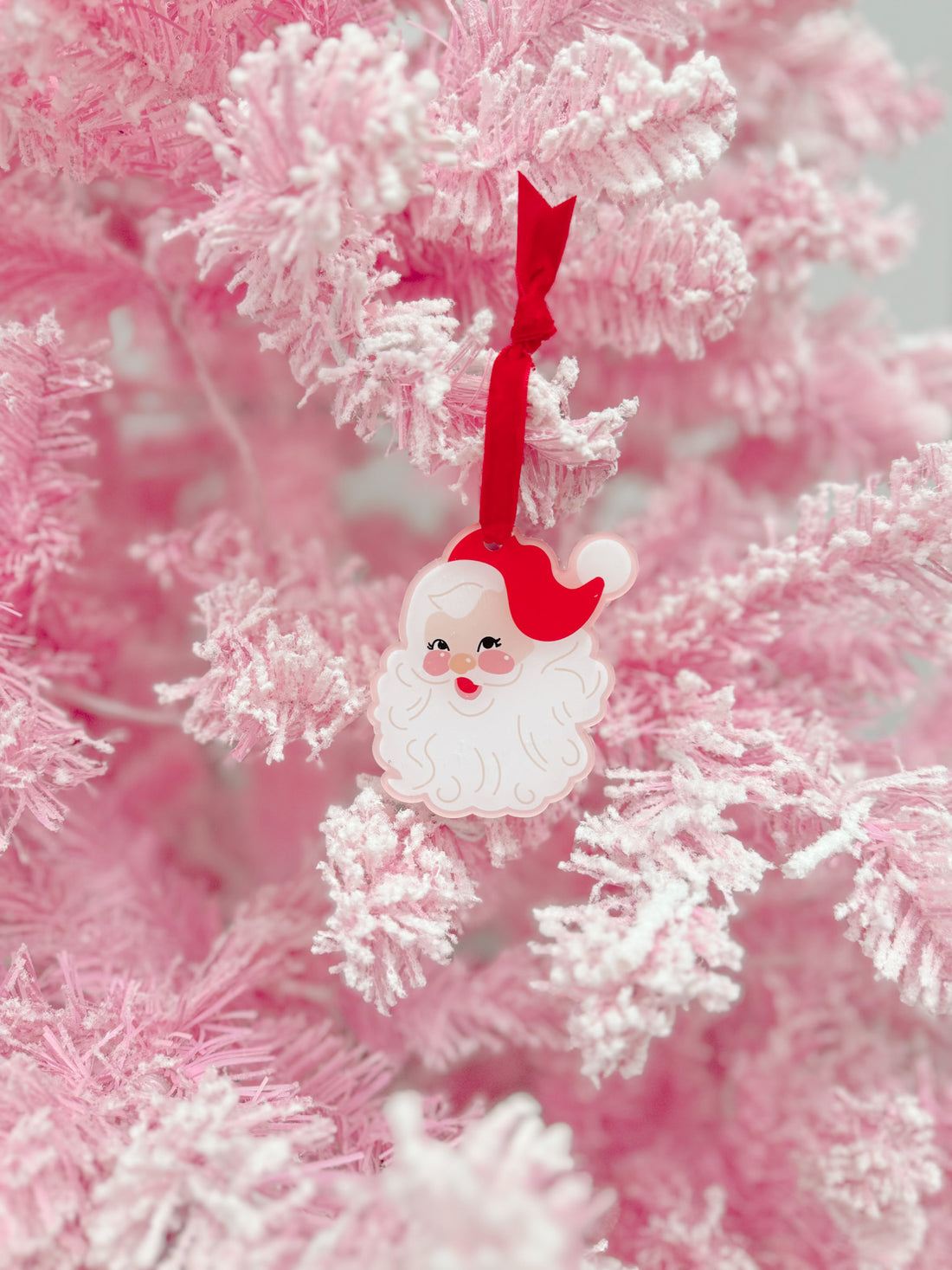 Charming Santa ornament hanging on a pink flocked Christmas tree.

