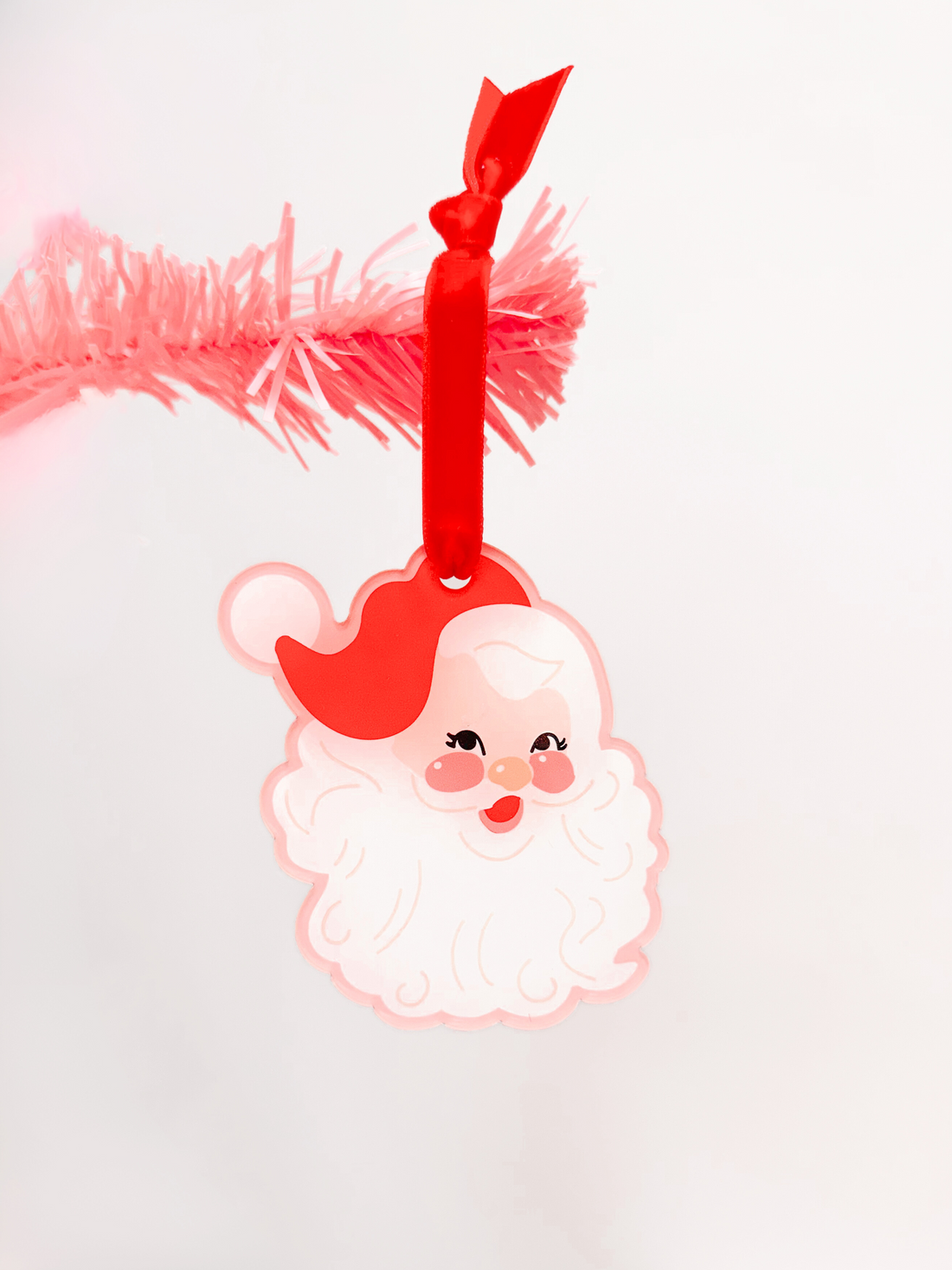 Pink Dear Santa ornament with red ribbon and hat, perfect Christmas tree decoration.
