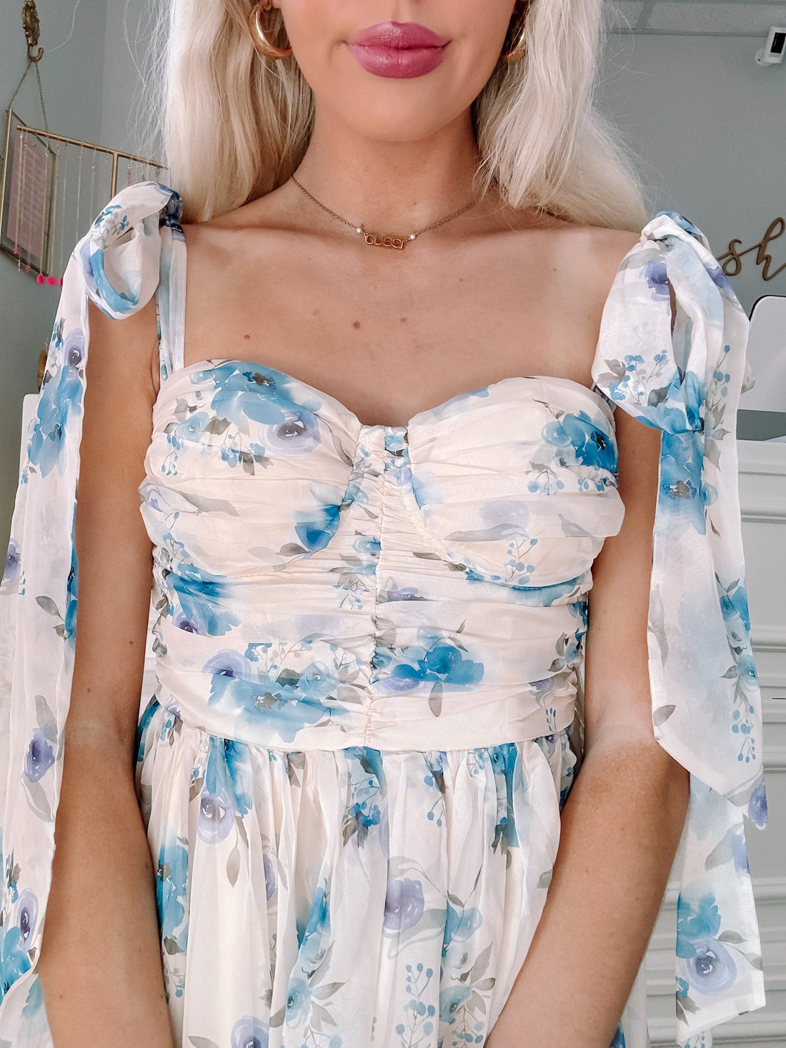 Cream-colored floral dress with blue accents, featuring ribbon shoulder straps.
