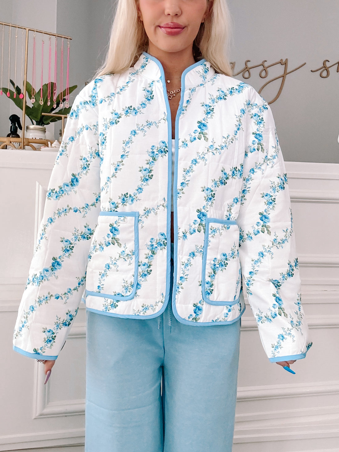 Floral Crest Quilted Jacket in blue, featuring a white background with blue floral print and light blue trim.
