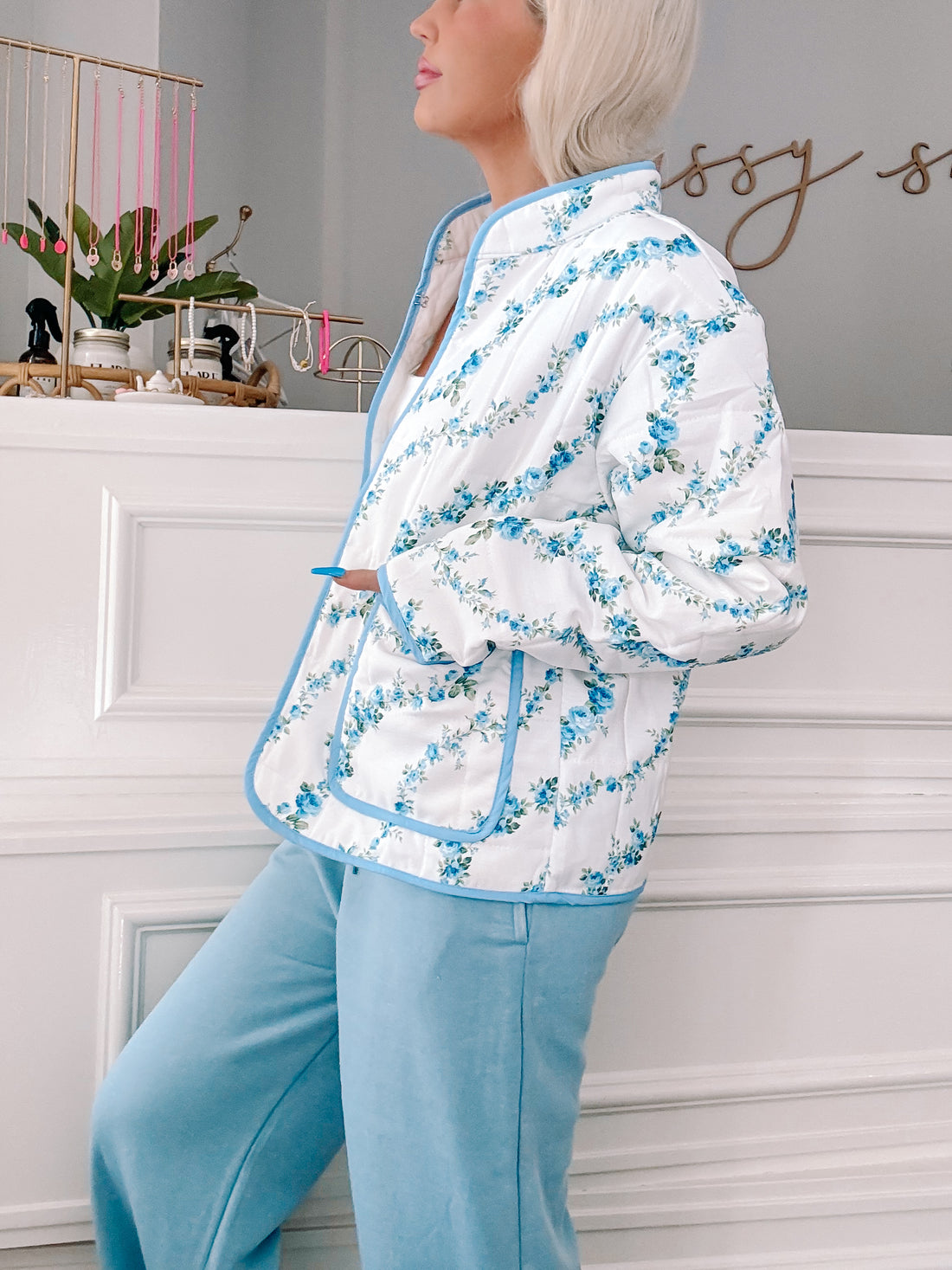 Blue floral quilted jacket with light blue trim, shown on model.
