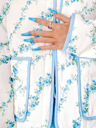 Blue floral quilted jacket detail shot, showcasing a light blue trim and delicate rose print.
