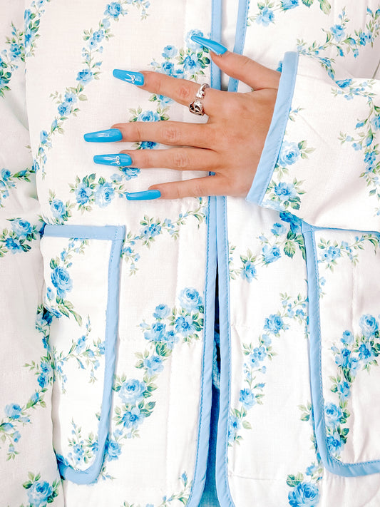Blue floral quilted jacket detail shot, showcasing a light blue trim and delicate rose print.