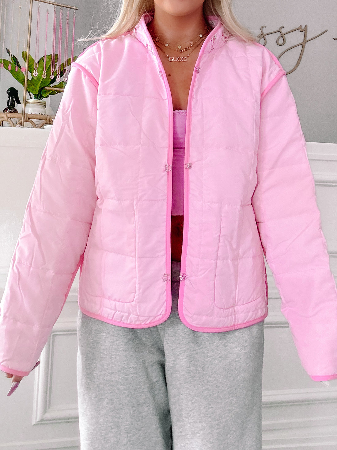 Pink quilted jacket with floral accents, shown on a model.
