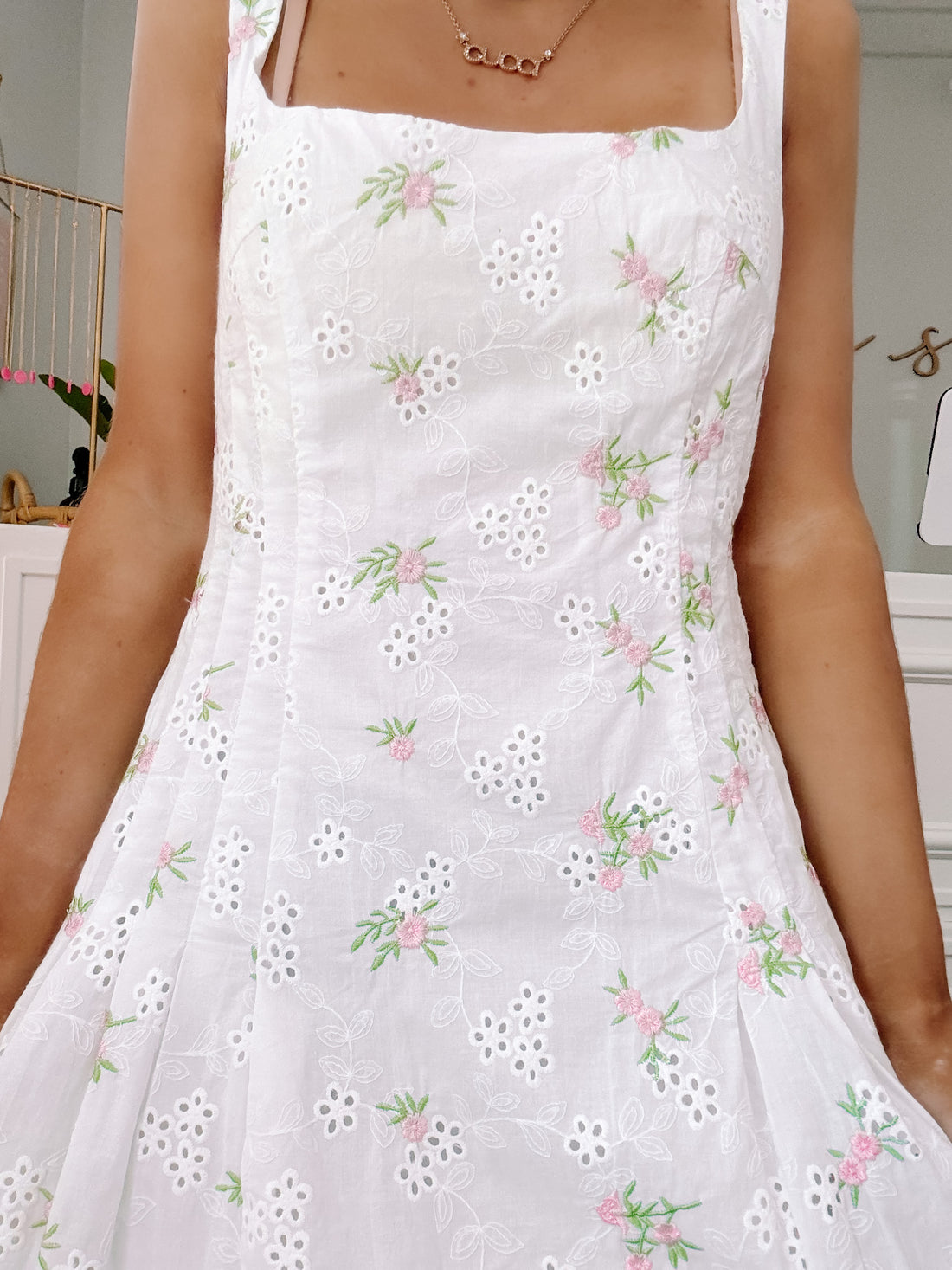 Close-up of eyelet embroidery and floral design on white mini dress