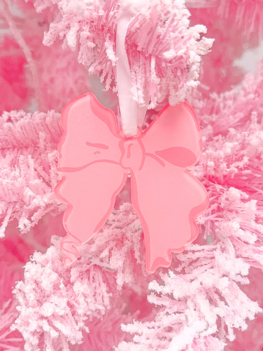Pink resin bow ornament hanging on a fluffy pink Christmas tree.