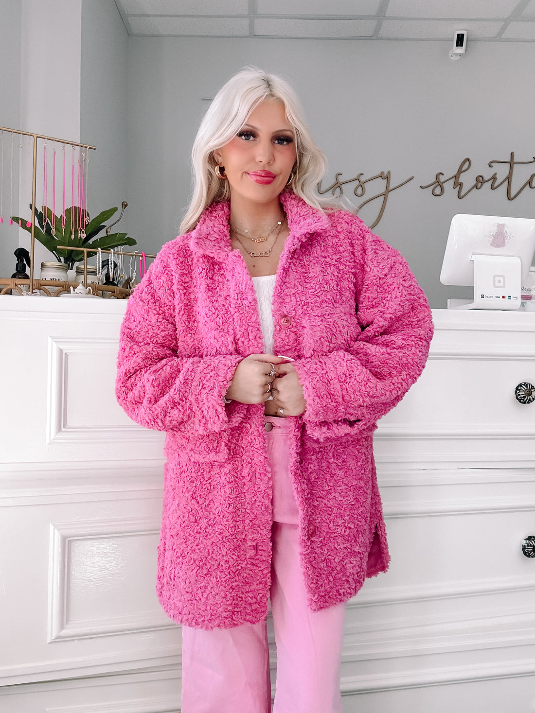 Fuzzy pink jacket styled with matching pants, worn indoors against a white backdrop.
