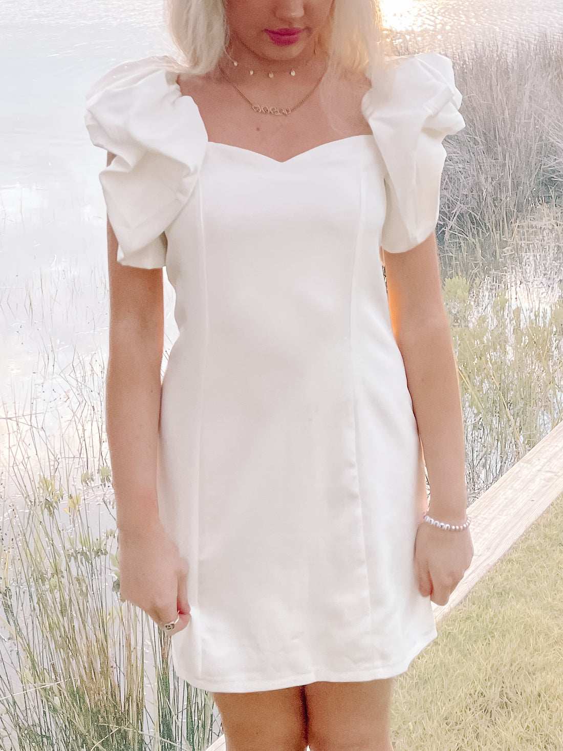 White puff-sleeve mini dress, sweetheart neckline.
