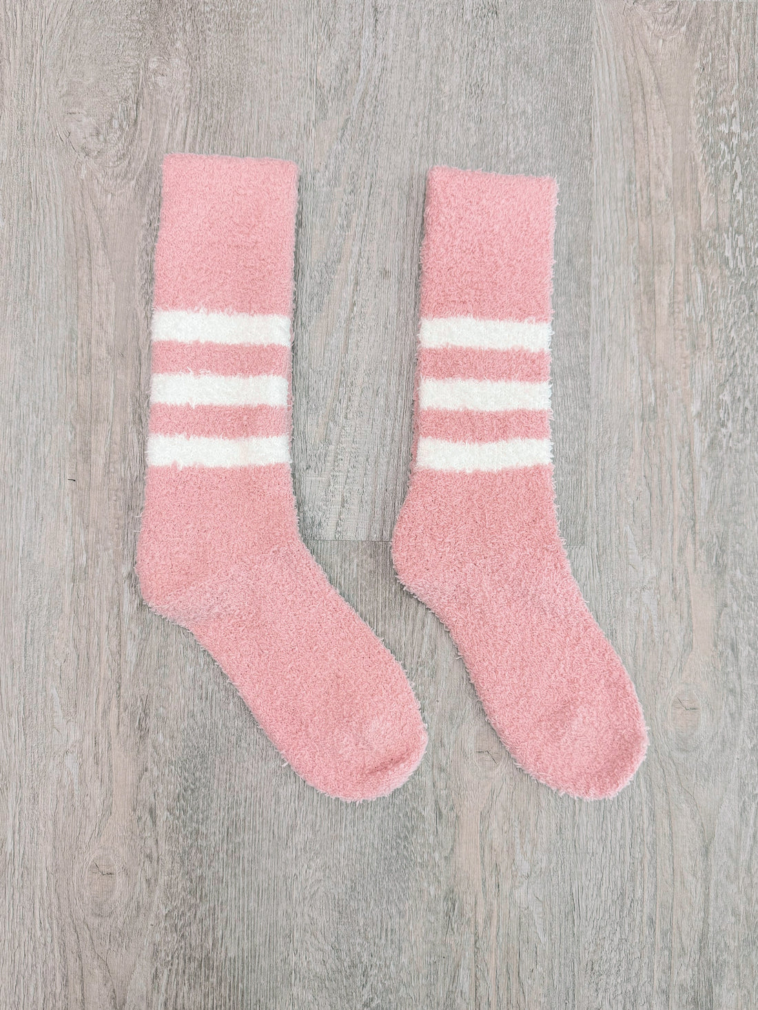 Fuzzy pink socks with white stripes for cozy comfort.
