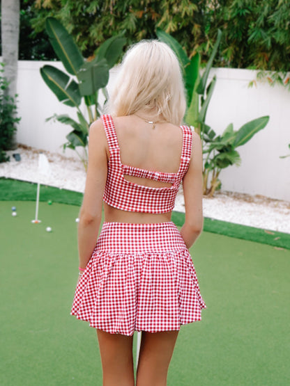 Game for Gingham Bubble Skirt by Sassy Shortcake  -  red and white checkered dress on a putting green with plants in the background
