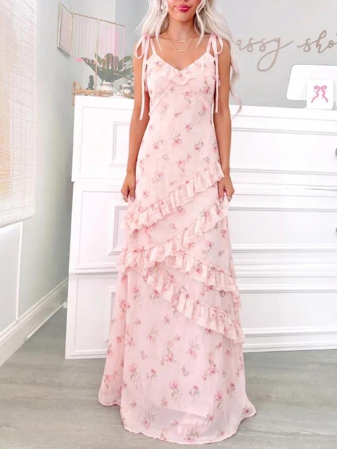 A blonde woman wearing a floor-length blush pink floral maxi dress with asymmetrical ruffles and tie-shoulder straps  Garden Romance Floral Maxi from Sassy Shortcake