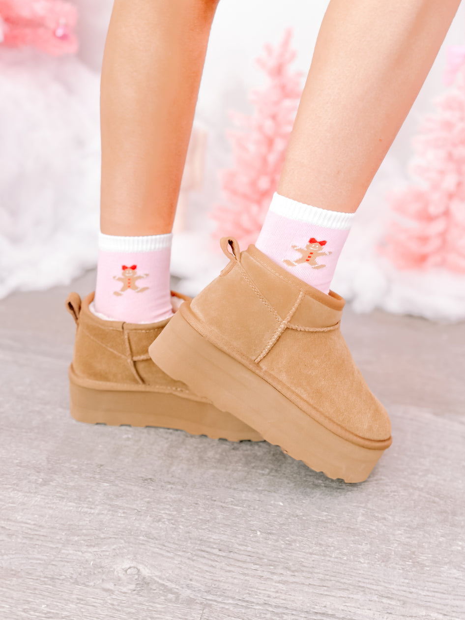 Tan platform boots with festive pink gingerbread socks featuring a cute illustration.
