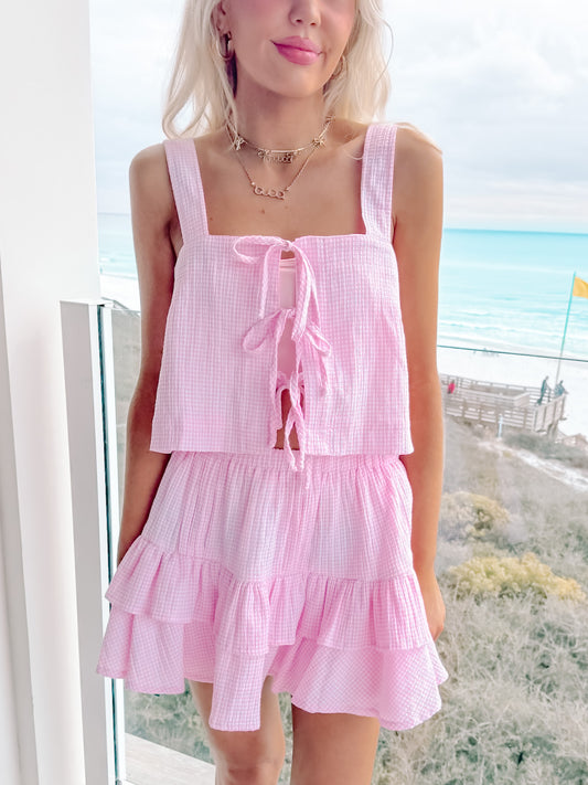 Model wearing pink gingham crop top and ruffle mini skirt set on a sunny day.