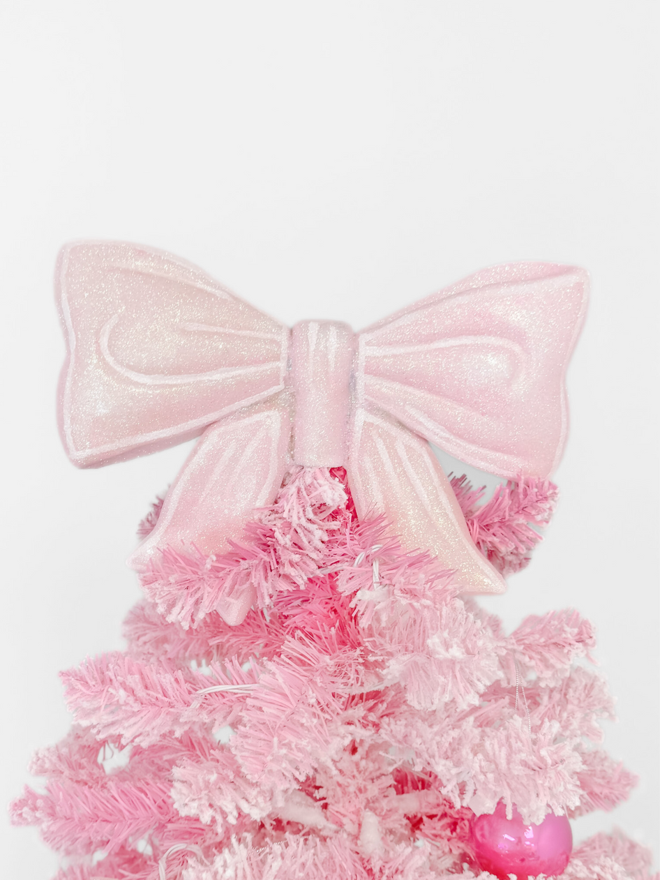 Pink glitter bow tree topper for a festive Christmas tree.
