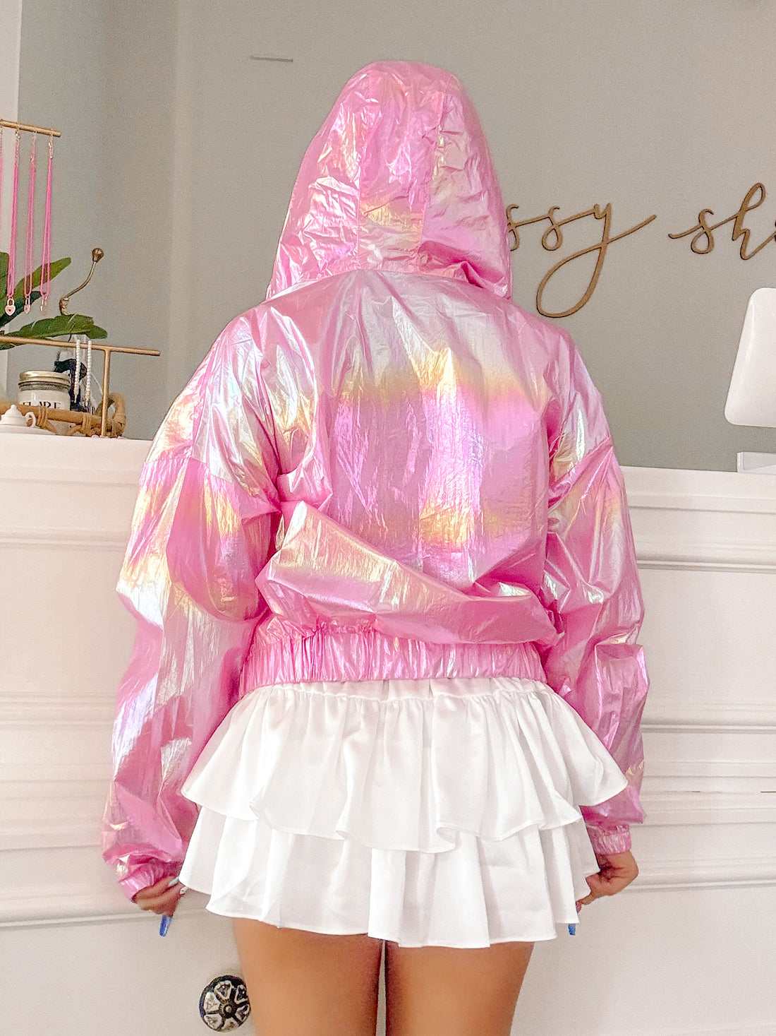Pink iridescent jacket with a hoodie, shown from the back, paired with a white ruffled skirt.
